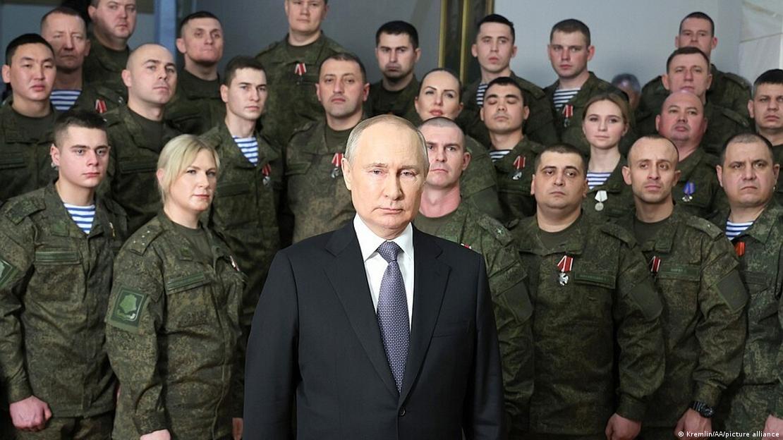 Vladimir Putin (önde) ve askeri üniforma giyen bir grup asker (arkada)