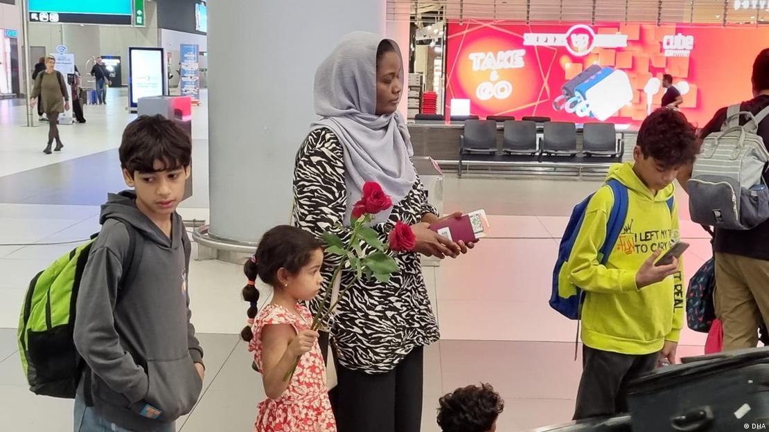 Sudan'dan Türkiye'ye getirilenler arasında bulunan kişilerden bir kadın ve dört çocuk bagajlarını bekliyor
