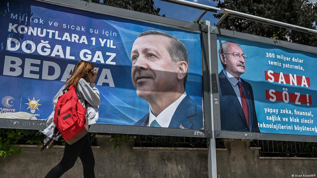 Cumhurbaşkanı adayları Kemal Kılıçdaroğlu ile Recep Tayyip Erdoğan'ın seçim afişleri önünde yürüyen bir kadın