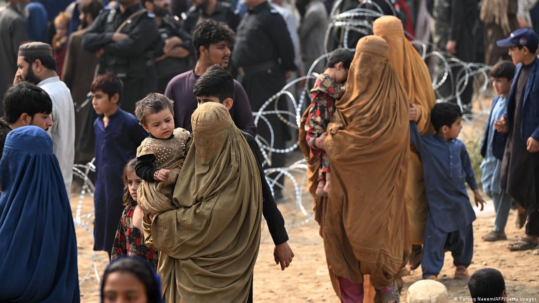 Kucaklarında çocukları ile burkalı Afgan kadınlar, arka planda dikenli teller ve kalabalık - (01.11.2023)